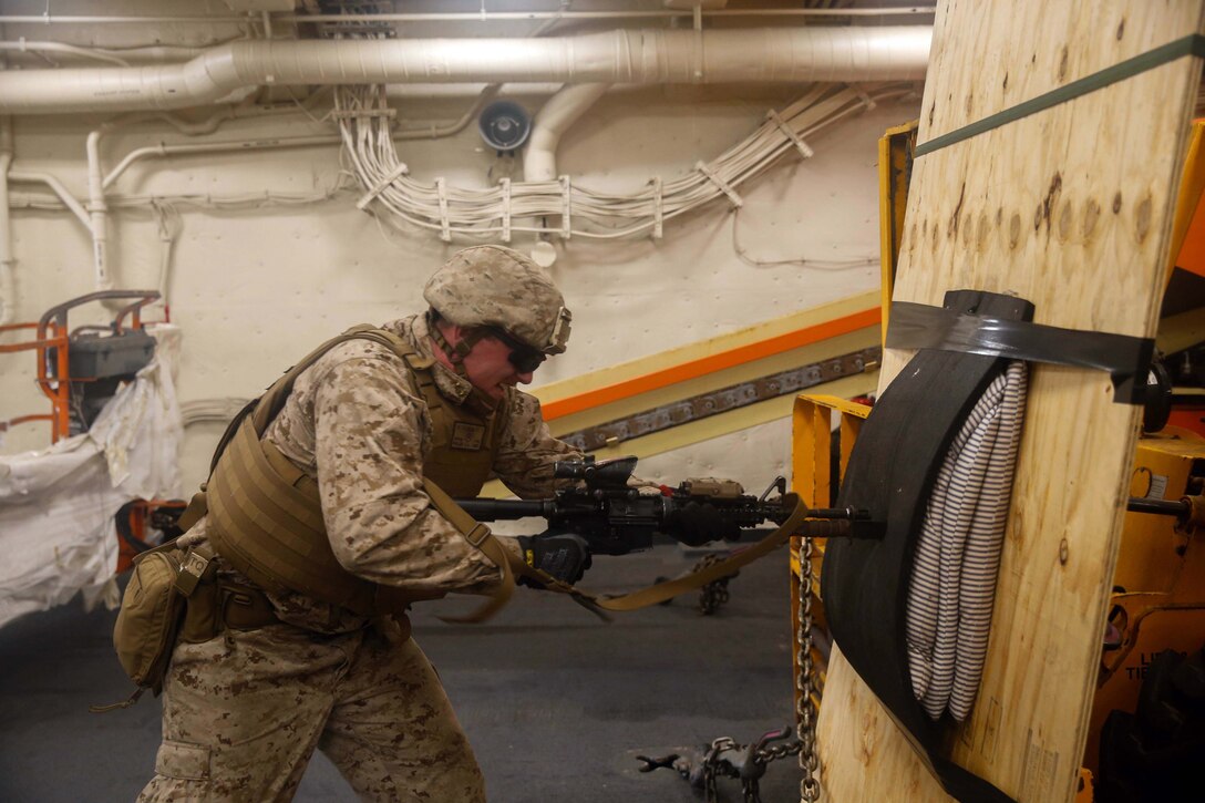 A Marine pushes a blade at the end of a firearm into a pad.