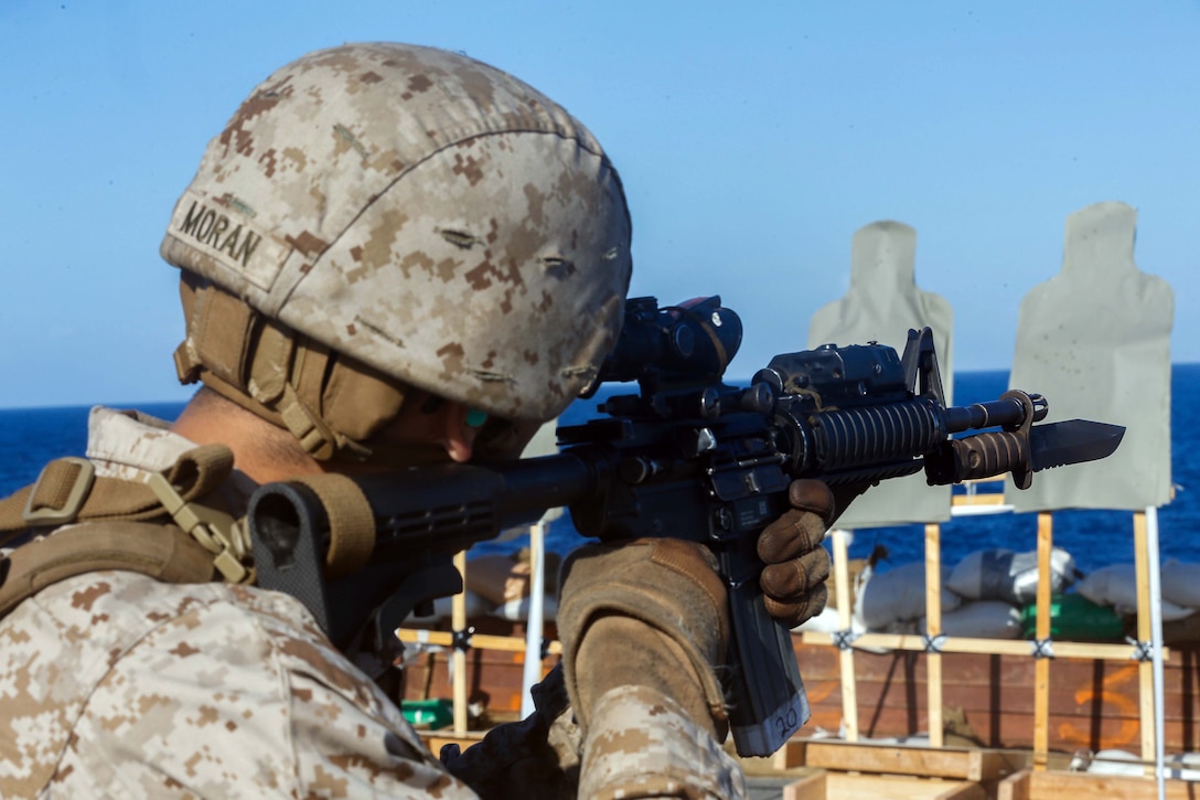 A Marine aims a firearm.