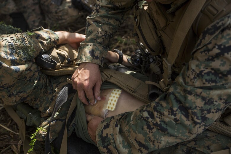 Hospitalman Third Class Timothy Lucsom checks the wound of a Marine role playing as a downed pilot during a Tactical Recovery of Aircraft and Personnel training event in Exercise Bougainville II at Landing Zone Boondocker, Marine Corps Base Hawaii, on Oct. 26, 2017. HM3 Lucsom is a corpsman with 2nd Battalion, 3rd Marine Regiment, and a native of Buffalo, N.Y. Exercise Bougainville II prepares 2nd Bn., 3rd Marines for service as a forward deployed force in the Pacific by training them to fight as a ground combat element in a Marine Air-Ground Task Force. (U.S. Marine Corps photo by Lance Cpl. Isabelo Tabanguil)