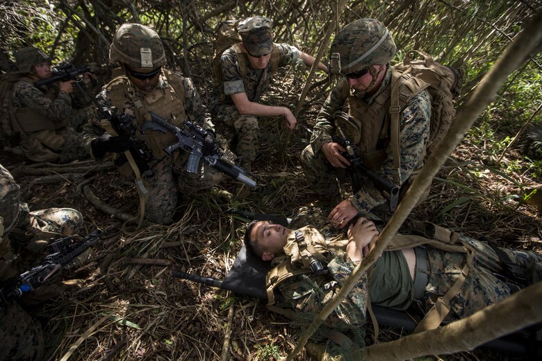 Cpl. Nathan Blue (left), Hospitalman Second Class Jonathan Alexander (middle), and Hospitalman Third Class Timothy Lucsom (right), oversee 2nd Lt. Mark Mabry playing a simulated downed pilot during a Tactical Recovery of Aircraft and Personnel training event in Exercise Bougainville II at Landing Zone Boondocker, Marine Corps Base Hawaii, on Oct. 26, 2017. Cpl. Blue is a mortarman, and a native of El Paso, Texas. HM2 Alexander and HM3 Lucsom are corpsmen. HM2 Alexander is a native of Colorado Springs, Colo., and HM3 Lucsom is a native of Buffalo, N.Y. 2nd Lt. Mabry is an infantry officer, and is a native of Benson, Ariz. All Marines and Sailors are with 2nd Battalion, 3rd Marine Regiment. Exercise Bougainville II prepares 2nd Bn., 3rd Marines for service as a forward deployed force in the Pacific by training them to fight as a ground combat element in a Marine Air-Ground Task Force. (U.S. Marine Corps photo by Lance Cpl. Isabelo Tabanguil)