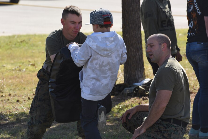 U.S. Marine Pfc. Stephn Dorn, Marine Corps Detachment at Goodfellow Air Force Base trainee, holds a pad while Staff Sgt. Calvin Bradbury, MCD instructor, teaches self-defense to a child during the Santa’s Market and Community Appreciation Day at the Louis F. Garland Department of Defense Fire Academy on Goodfellow Air Force Base, Texas, Nov. 18, 2017. The MCD offered hand-to-hand lessons to anyone interested and provided step-by-step guidance on each exercise. (U.S Air Force photo by Airman 1st Class Zachary Chapman/Released)