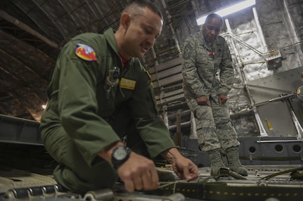 Tech. Sgt. Mitchell Thompson, 15th Airlift Squadron loadmaster flight chief of training, demonstrates how to secure an extraction line bag to the ramp of a C-17 Globemaster III for aircrew members and Chief Master Sgt. Shelina Frey, Air Mobility Command command chief, on a C-17 on the flightline in Joint Base Charleston, S.C., Nov. 17, 2017.