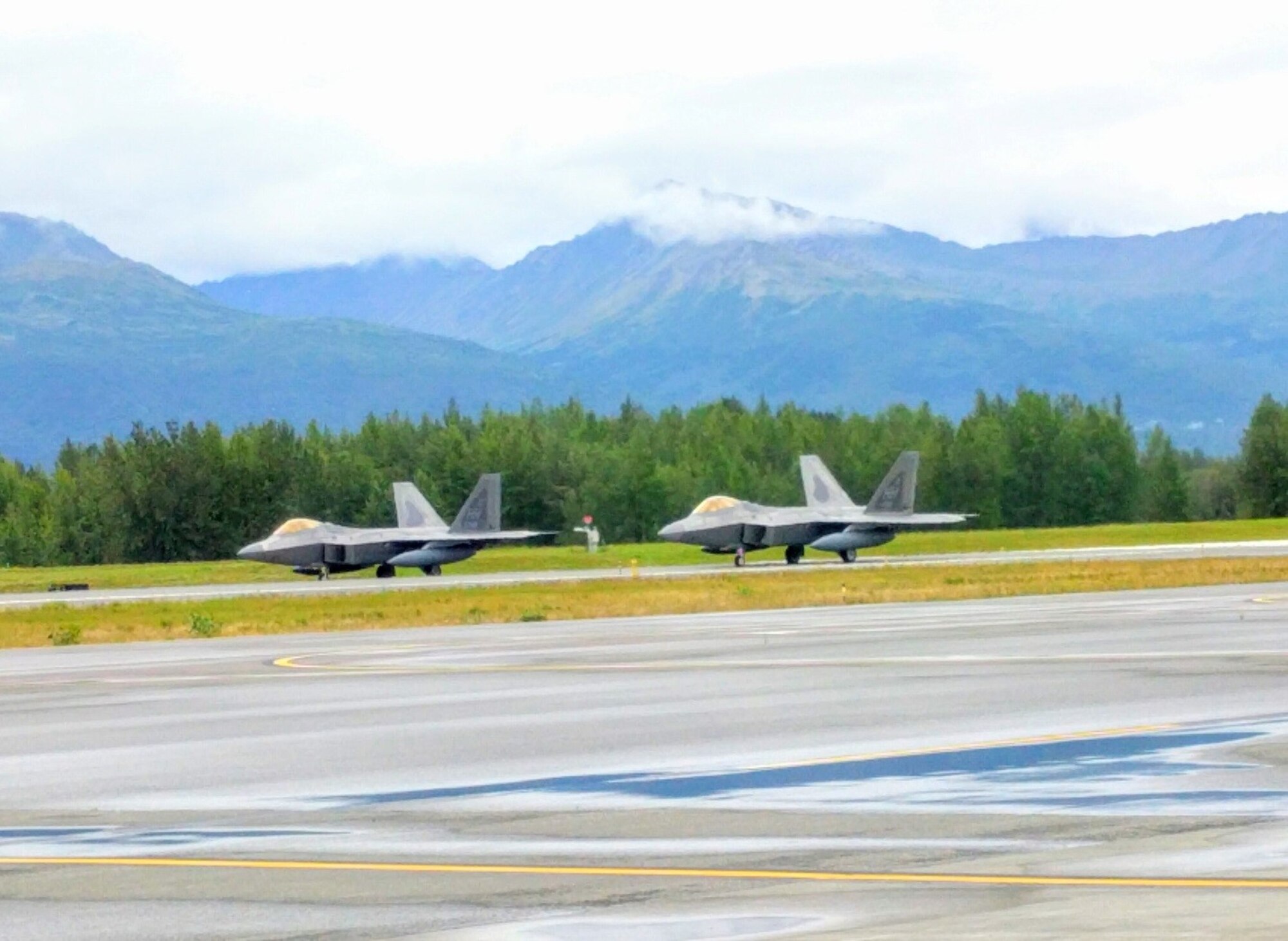 Two F-22 Raptor aircraft prepare to take off during an Air Force Operational Energy mission at Joint Base Elmendorf-Richardson in Anchorage, Alaska, August 13, 2017. The aircraft were part of a demonstration to assess if flying at an increased speed consumes less fuel and while saving precious flight hours.