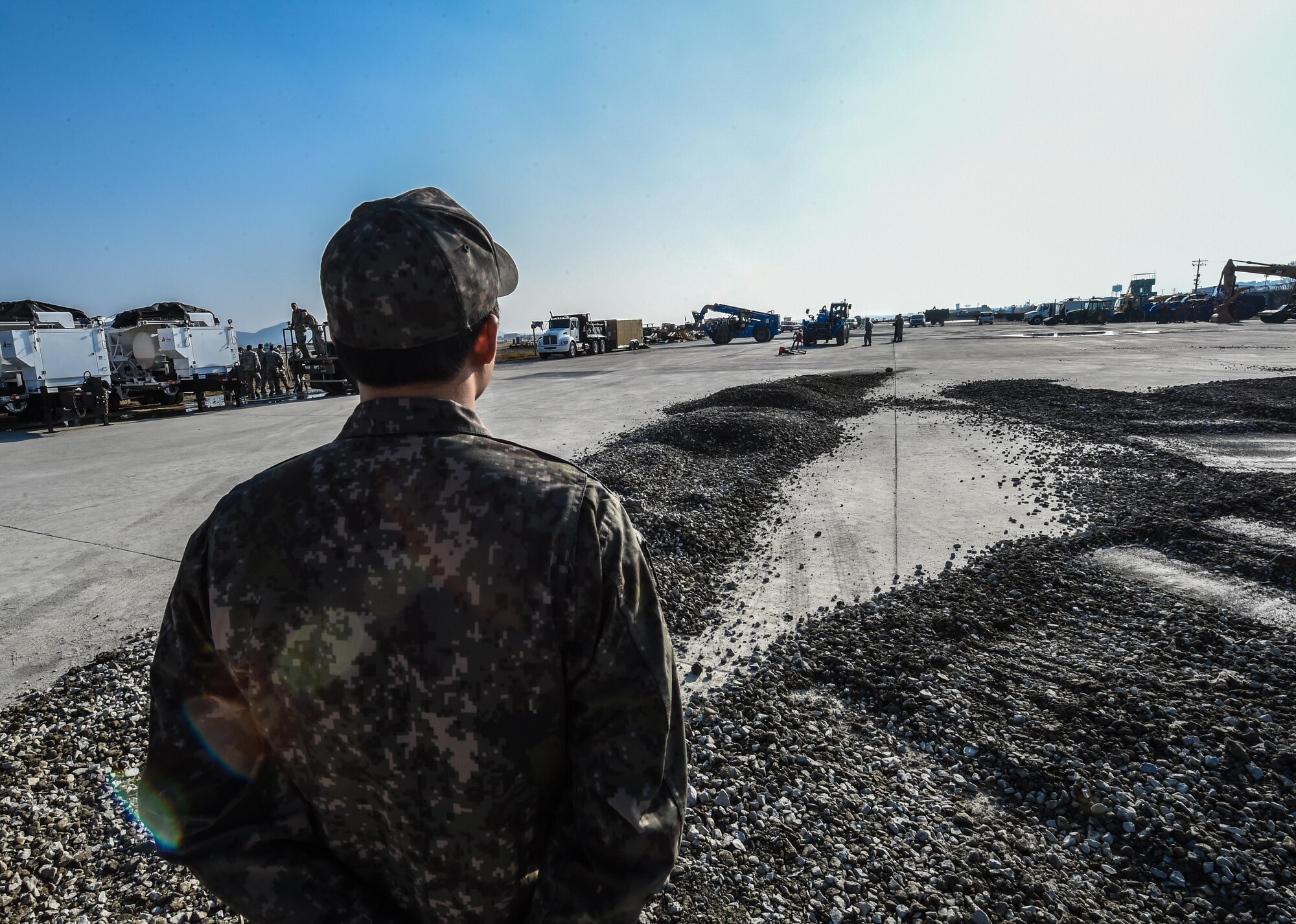 Republic of Korea Air Force Sgt. Kihyun Shim, communications specialist, observes a Rapid Airfield Damage Repair exercise on the airfield at Gwangju Air Base, R.O.K., Nov. 6, 2017. Approximately forty U.S. Airmen from the 773d Civil Engineer Squadron at Joint Base Elmendorf-Richardson, Alaska, and 40 Republic of Korea Airmen from Gwangju trained together for a week to learn a new runway repair process for wartime contingencies. The RADR process makes use of rapid-setting concrete which enables vehicles to pass over it after one hour; after two hours of cure time, it can support any aircraft. (U.S. Air Force photo by Senior Airman Curt Beach)