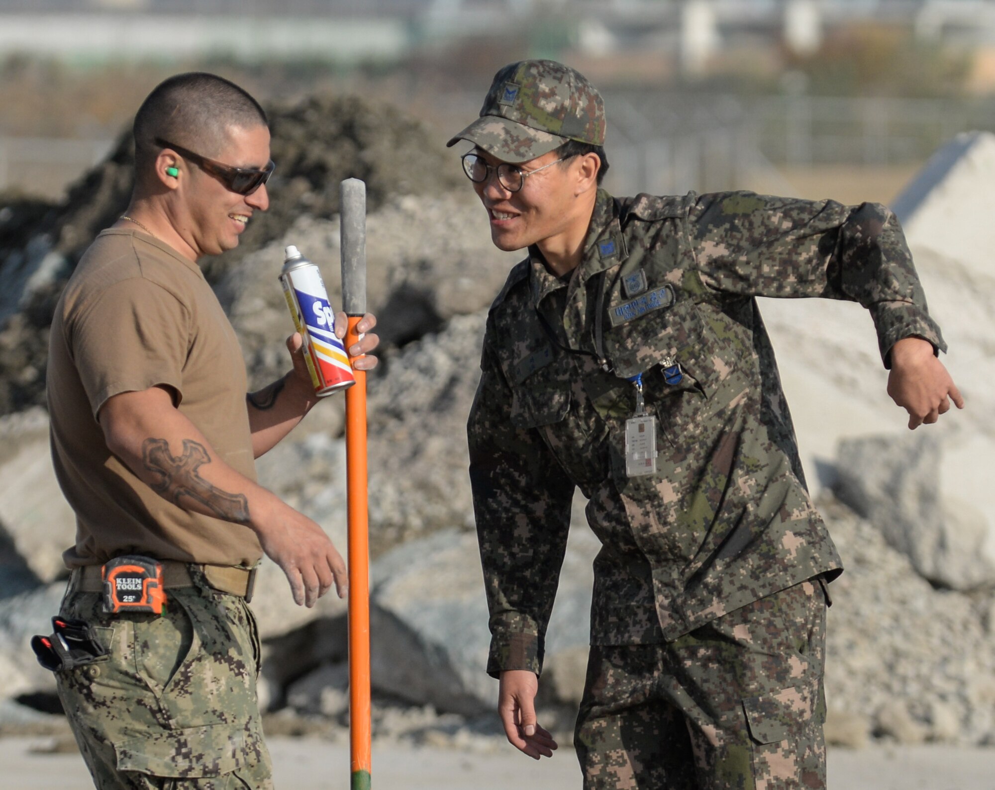 A U.S. Navy Seaman and a Republic of Korea Air Force Airman interact during a Rapid Airfield Damage Repair training exercise at Gwangju Air Base, R.O.K., Nov. 8, 2017. Similar to an assembly line, RADR systematically lines up civil engineer personnel and equipment to quickly repair a runway after attack. The training exercise was designed to enhance interoperability, prepare for wartime contingencies and build partnership capacity in the Indo-Asia Pacific region. (U.S. Air Force photo by Senior Airman Curt Beach)