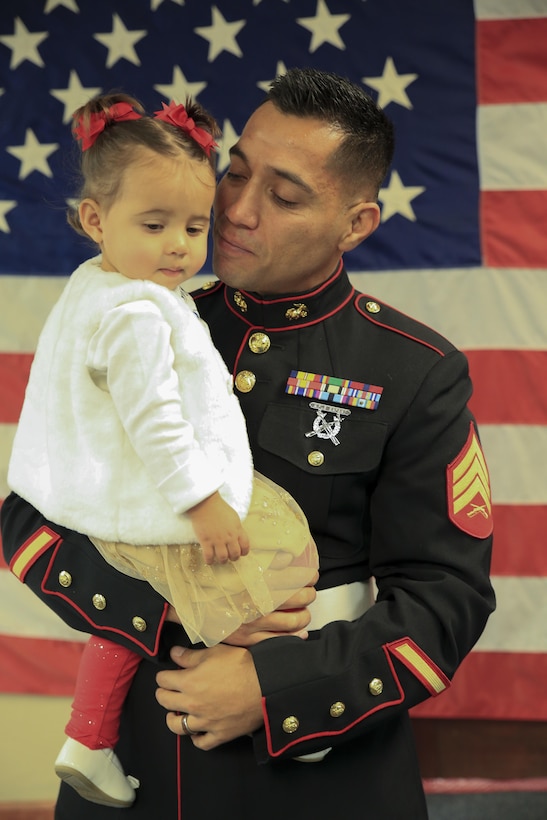 Marine Corps veteran Sgt. Eubaldo Lovato, a Silver Star recipient, holds his daughter prior to his Silver Star award ceremony in Montrose, Colo., Nov. 18, 2017.