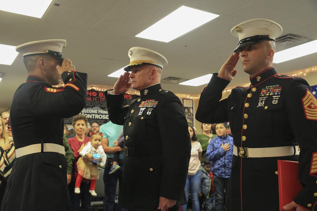 Marine Corps veteran Sgt. Eubaldo Lovato (left), Silver Star recipient, Brig. Gen. Michael Martin (center), deputy commanding general of Marine Corps Forces Command, and Sgt. Maj. Bryan Fuller, Inspector Instructor Sgt. Maj. of Combat Logistics Group 453 Sgt. Maj., 4th Marine Logistics Group, render honors during the playing of the National Anthem during the Silver Star award ceremony in Montrose, Colo., Nov. 18, 2017.