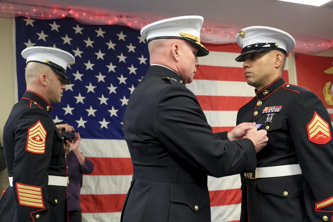 Sgt. Maj. Bryan Fuller (left), Inspector Instructor Sgt. Maj. of Combat Logistics Group 453, and Brig. Gen. Michael Martin (center), Deputy Commanding General of Marine Corps Forces Command, present Marine Corps veteran Sgt. Eubaldo Lovato (right), with the Silver Star award in Montrose, Colorado, Nov. 18, 2017.