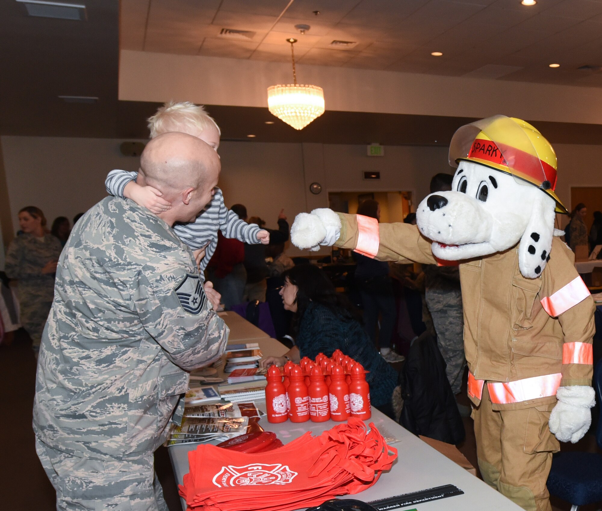 Sparky, the Fire Rescue mascot, fist bumps a child at the Warren Top 3 craft fair and health fair on F.E. Warren  Air Force Base Wyo., Nov. 17, 2017. Squadrons from all across the wing and members from the community set up booths to help promote health, safety or to just sell their crafts. (U.S. Air Force photo by Airman 1st Braydon Williams)