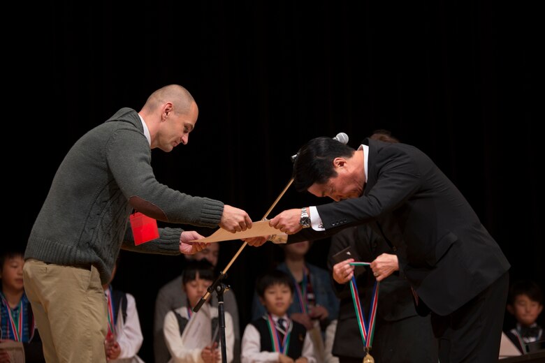 U.S. Marine Corps Capt. Eliot V. Rasmussen, left, receives a first-place award for the adult Japanese speeches division from Bobby Shibazaki, the Japanese American Society president, during the 56th Annual Japanese and English Speech at Sinfonia Iwakuni Concert Hall in Iwakuni City, Japan, Nov. 19, 2017.  The contest was hosted by the Japanese American Society to help contestants understand and appreciate each other’s language and culture, strengthening the Japanese and American friendship.