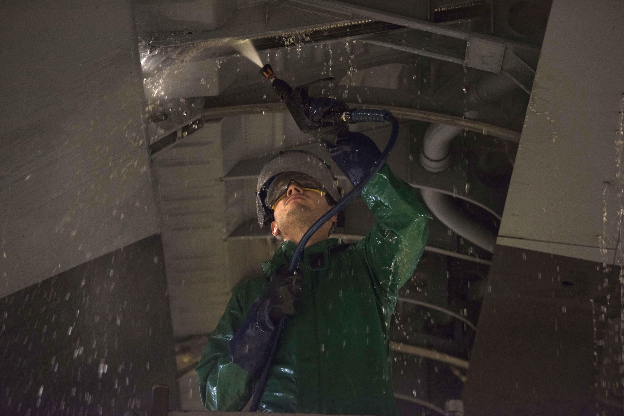 U.S. Air Force Airman 1st Class Samuel Crispin, C-130J Super Hercules crew chief, sprays hot water to clean the underside of a C-130J wing on Ramstein Air Base, Germany, Nov. 20, 2017. Airmen scrub the aircraft with a cleaning solution before they are sprayed down with hot water. (U.S. Air Force photo by Airman 1st Class Devin M. Rumbaugh)