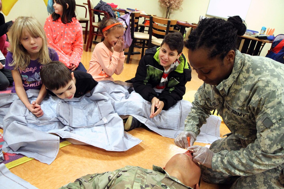 Children watch as an Army medic demonstrates first aid techniques.