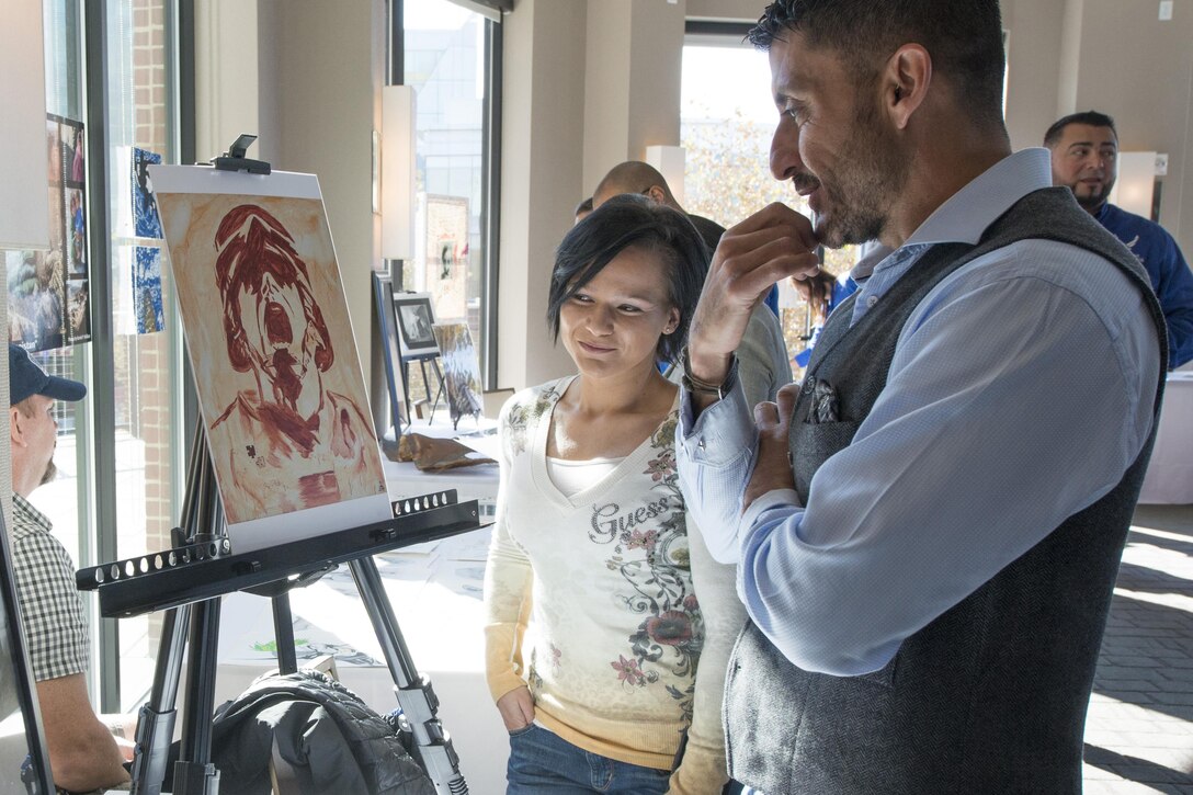 Two people stand next to each other looking at an unseen object.