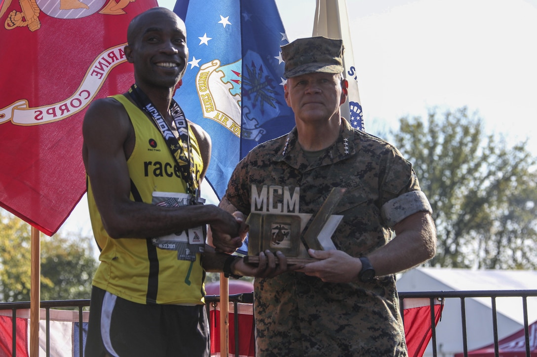 Commandant of the Marine Corps Gen. Robert B. Neller, right, presents a trophy to Denzel Ramirez, first place male finisher of the 9th Marine Corps Marathon (MCM) 10K, Arlington, Va., Oct. 22, 2017. Neller awarded trophies to the top three male and female finishers of the MCM and the MCM 10K.