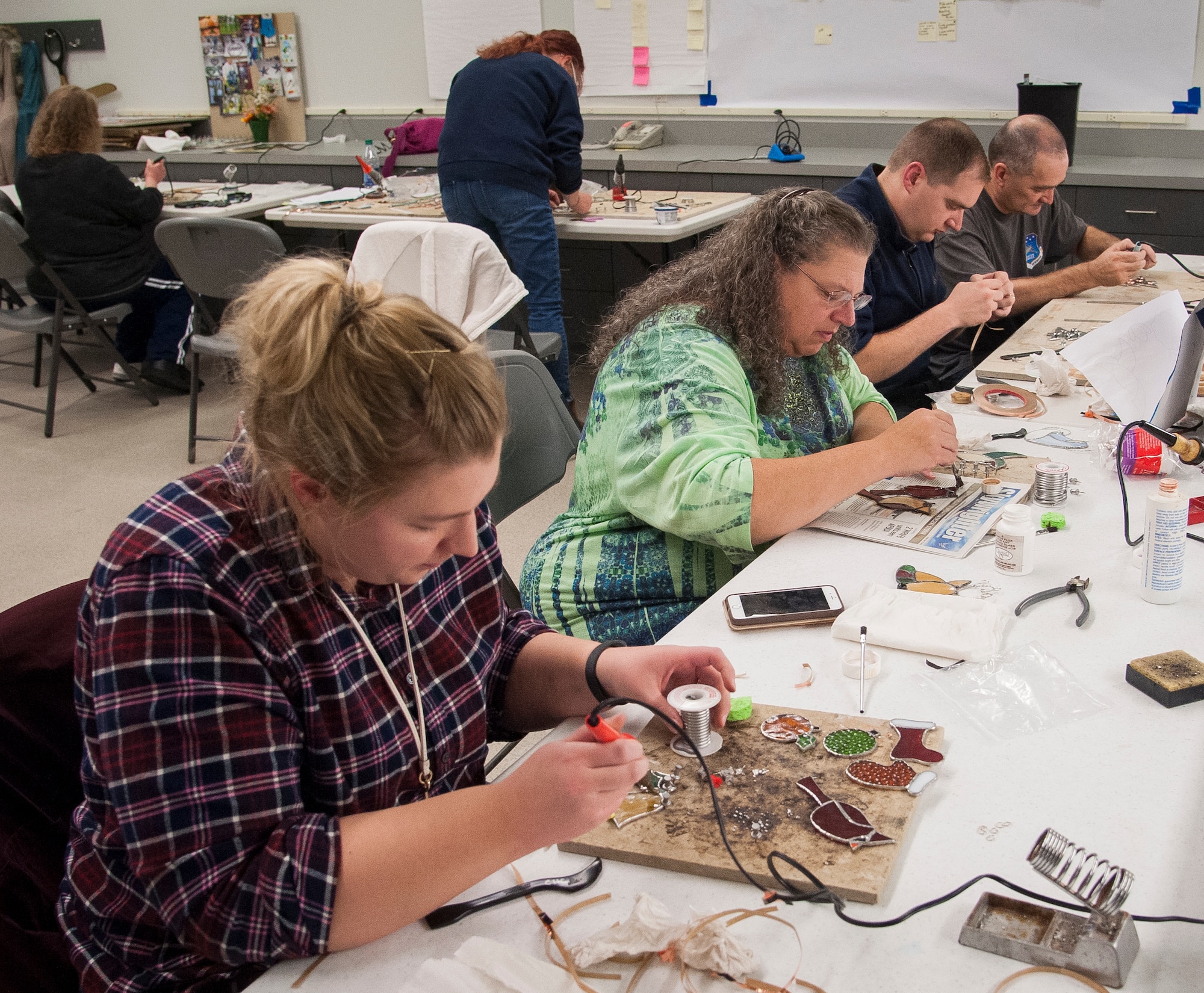 Family members from left: Laura, Theresa, Christopher, and Tom Rittenhouser work on their projects during a holiday themed stained glass workshop at the Consolidated Hobby Complex on Wright-Patterson Air Force Base, Ohio, Nov.18, 2017. Husband and wife Christopher and Laura took the workshop last year and liked it so much that they came back from another year and invited Christopher's parents Theresa and Tom to join them. (U.S. Air Force photo/Jim Varhegyi)