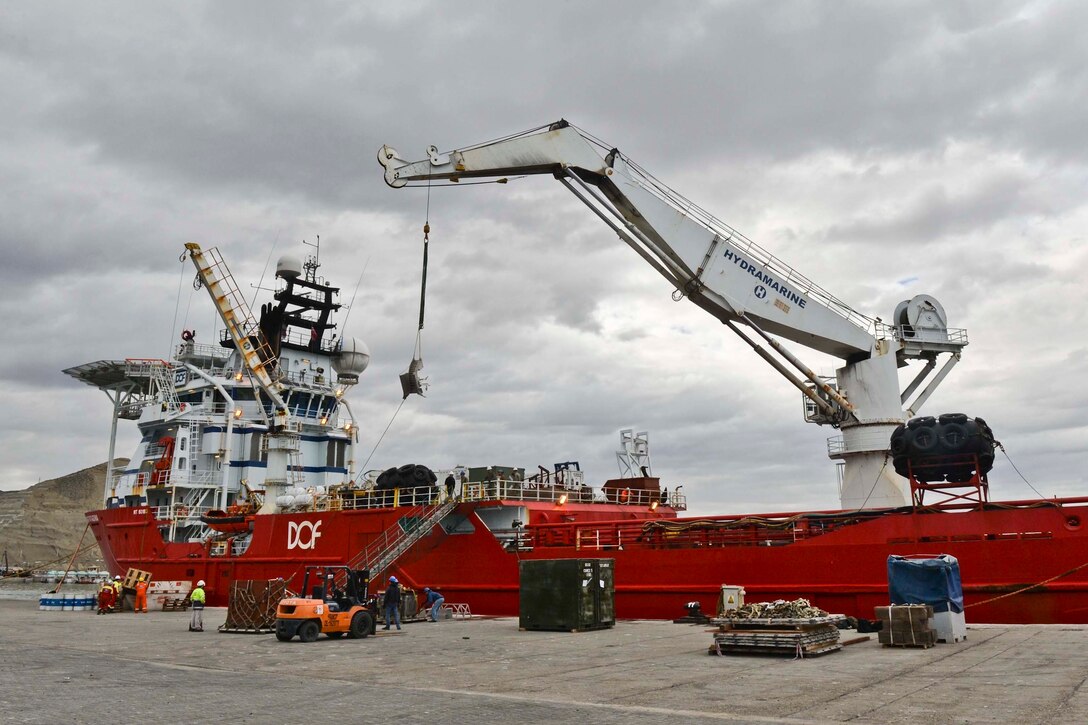 U.S. Sailors and Argentines load submarine rescue equipment onto a Norwegian construction support vessel