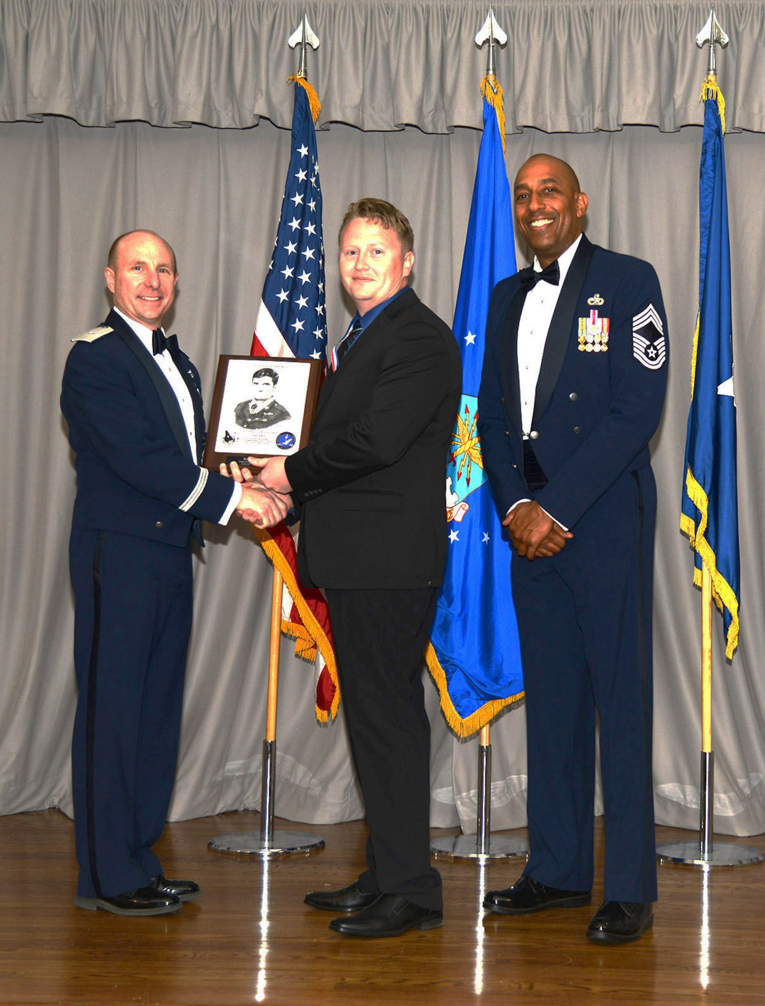 Brig. Gen. Carl Schaefer, 412th Test Wing commander, and Chief Master Sgt. Roosevelt Jones, 412th Test Wing command chief, present Robert Topp, a maintenance mechanic with the 412th Civil Engineer Group, the John L. Levitow Award at the Airman Leadership School graduation ceremony for class 18A. Topp was the first civilian to earn the Levitow award. (U.S. Air Force photo by Christopher Ball)