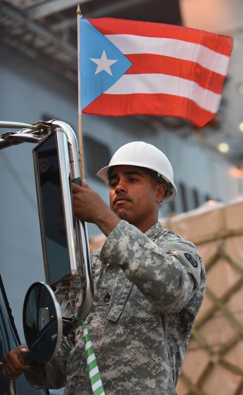 U.S. Army Staff Sgt. Eliezer Casas, 690th Rapid Port Opening Element, 832nd Transportation Battalion, 597th Trans. Brigade distribution yard NCO in charge, fixes a Puerto Rico flag on a vehicle at Port of Ponce, Puerto Rico, Nov. 7, 2017.