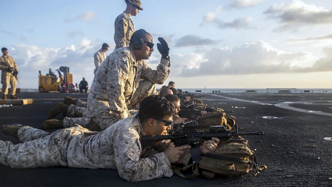 Marines participate in a live-fire exercise on a ship's deck.