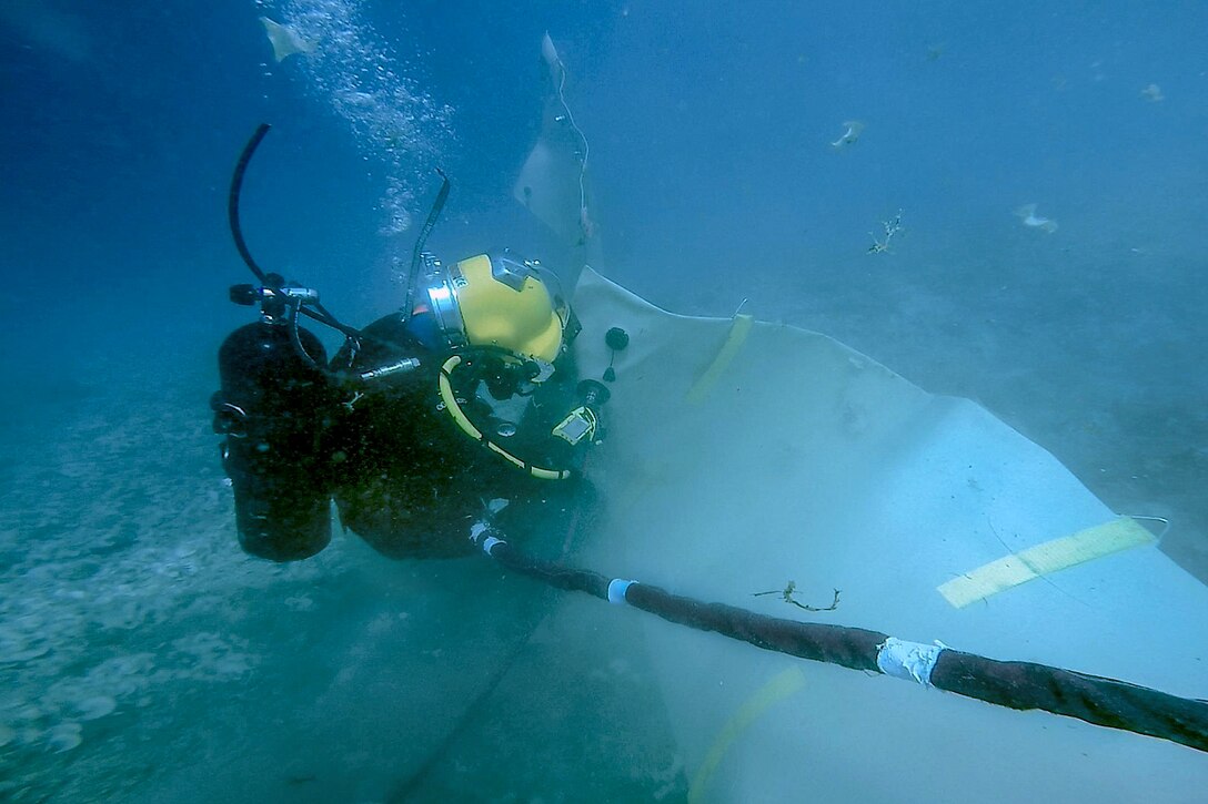 A diver attaches an air hose underwater in Guam.