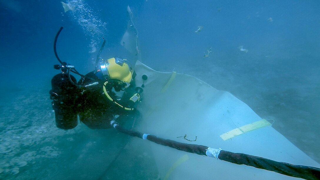 A diver attaches an air hose underwater in Guam.