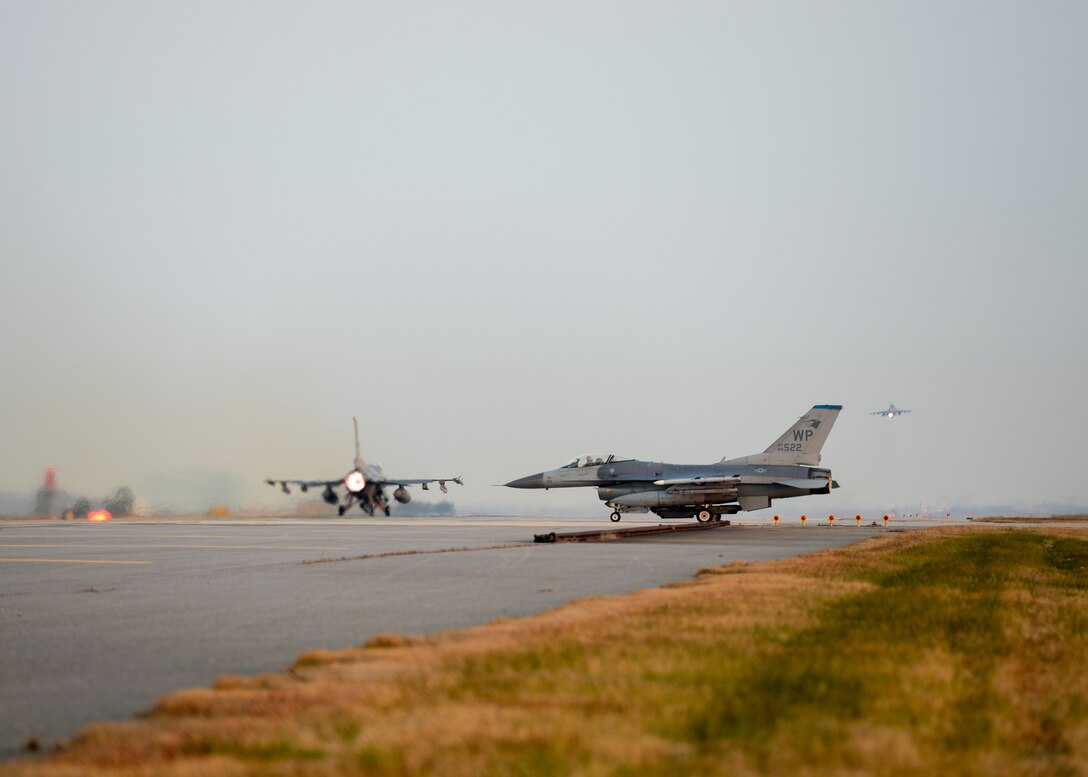 A U.S. Air Force F-16 Fighting Falcon with the 80th Fighter Squadron uses its afterburner to take off at Kunsan Air Base, Republic of Korea, Nov. 17, 2017, while a pilot with the 35th FS taxis to take off behind. The two fighter squadrons carry out a wide variety of combat sorties in support of contingency operation plans on the Korean Peninsula. These aircraft took part in a large force employment involving more than 20 aircraft to test their ability to conduct such missions. (U.S. Air Force photo by Capt. Christopher Mesnard)