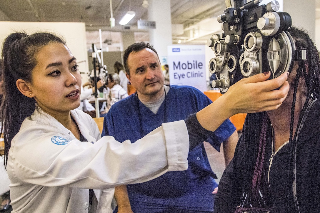 A soldier working as an optometrist oversees a student.