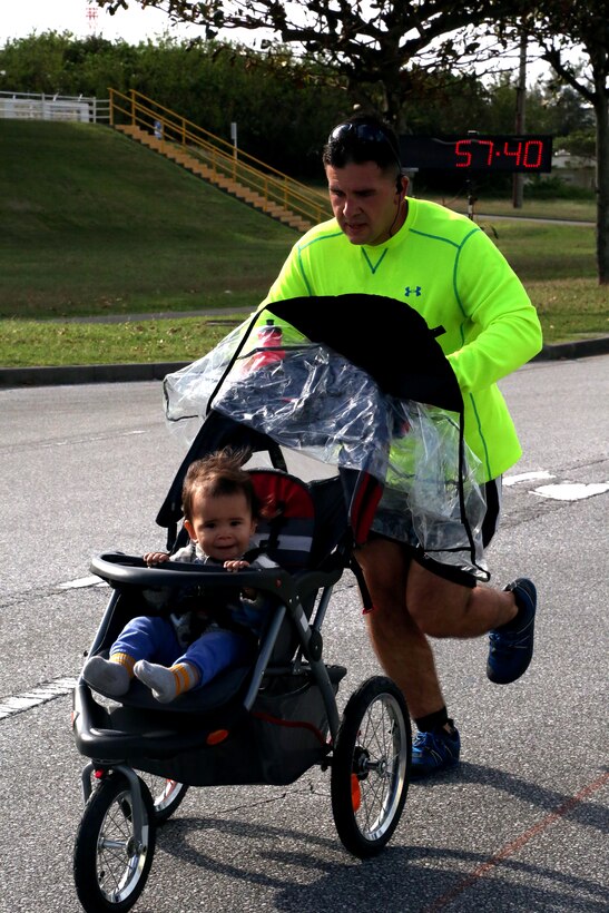 Capt. Miguel Garcia pushes his son during the 28th Annual Kinser Half Marathon Nov. 19 aboard Camp Kinser, Okinawa, Japan. The 13.1-mile run brought the local and military communities together for a friendly competition. Awards were given to the top three runners in each age category. Garcia is a supply officer with the Expeditionary Operations Training Group, III Marine Expeditionary Force Information Group.