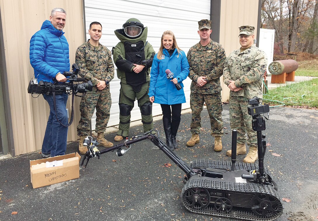 om left to right: Mike Rudd, WJLA, SSgt Alfredo Andrade, Explosive Ordinance Disposal (EOD) technician, Sgt. Wesley Buzzard EOD technician, Eileen Whelan, WJLA, Maj. A.J. Bormann director, Quantico office of Communication, and Master Gunnery Sgt. David Alexander EOD chief, demonstrate how they approach suspicious packages
