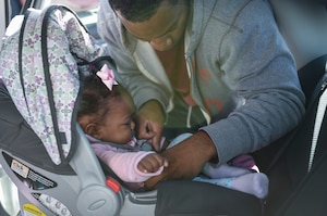 Staff Sgt. Martell Chandler, 315th Aerospace Medical Squadron dental technician straps his eight-month-old daughter, Ava, to her car seat during the Safe Kids Charleston Area car seat assessment in the Hunt Community Center parking lot on Joint Base Charleston, S.C., Nov. 20, 2017.