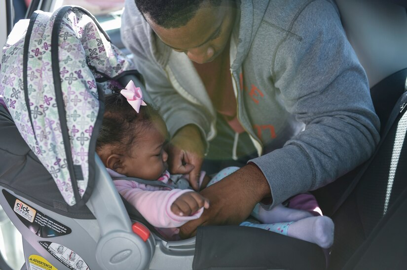 Staff Sgt. Martell Chandler, 315th Aerospace Medical Squadron dental technician straps his eight-month-old daughter, Ava, to her car seat during the Safe Kids Charleston Area car seat assessment in the Hunt Community Center parking lot on Joint Base Charleston, S.C., Nov. 20, 2017.