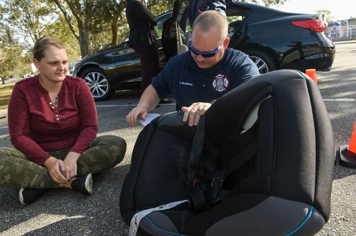 Samantha Aglubat, a military spouse, left, observes Glenn McLendon, Summerville Fire Department engineer, right, inspect her child’s car seat during the Safe Kids Charleston Area car seat assessment at the Hunt Community Center parking lot on Joint Base Charleston, Nov. 20, 2017.