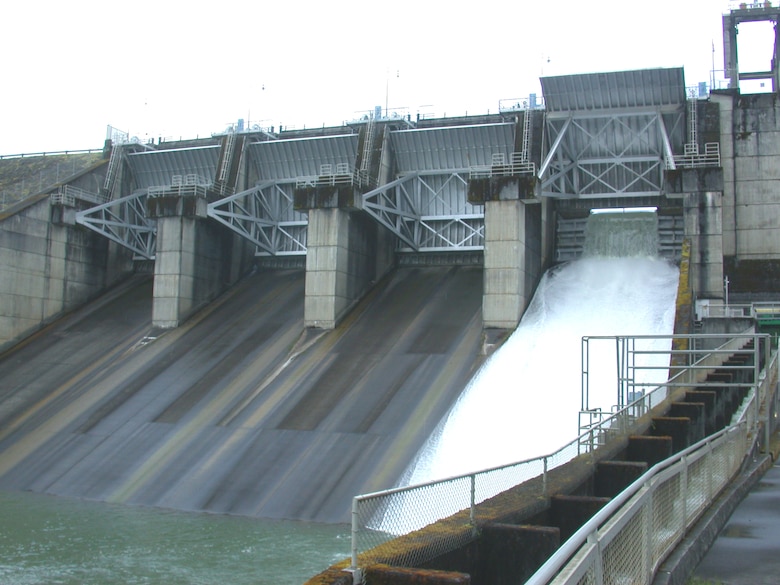 Water flows out of Foster Dam through a ‘fish weir’ (right spillway), Sweet Home, Ore. A fish weir is a structure that the Corps places in a dam’s spillway to manage water for juvenile fish passage. The weir constrains the release of water to maintain flow requirements, provides attraction for fish (stream-like flow from the surface of the reservoir) and creates a ‘cushion’ of water when striking the spillway. This cushion helps fish survive the fall. The Corps is removing a crane (upper right) to install a new weir.