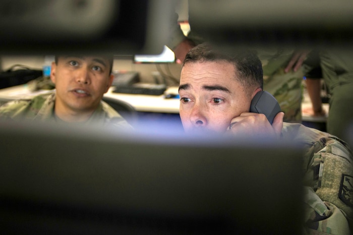 Two soldiers look at computers.