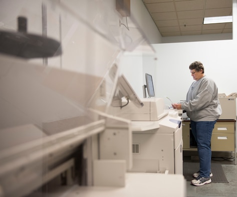 Photo of Teresa Blake, Documentation Automation Printing Services electronic duplicating system operator, inspecting a print job at Mountain Home Air Force Base, Idaho, Nov. 16, 2017.