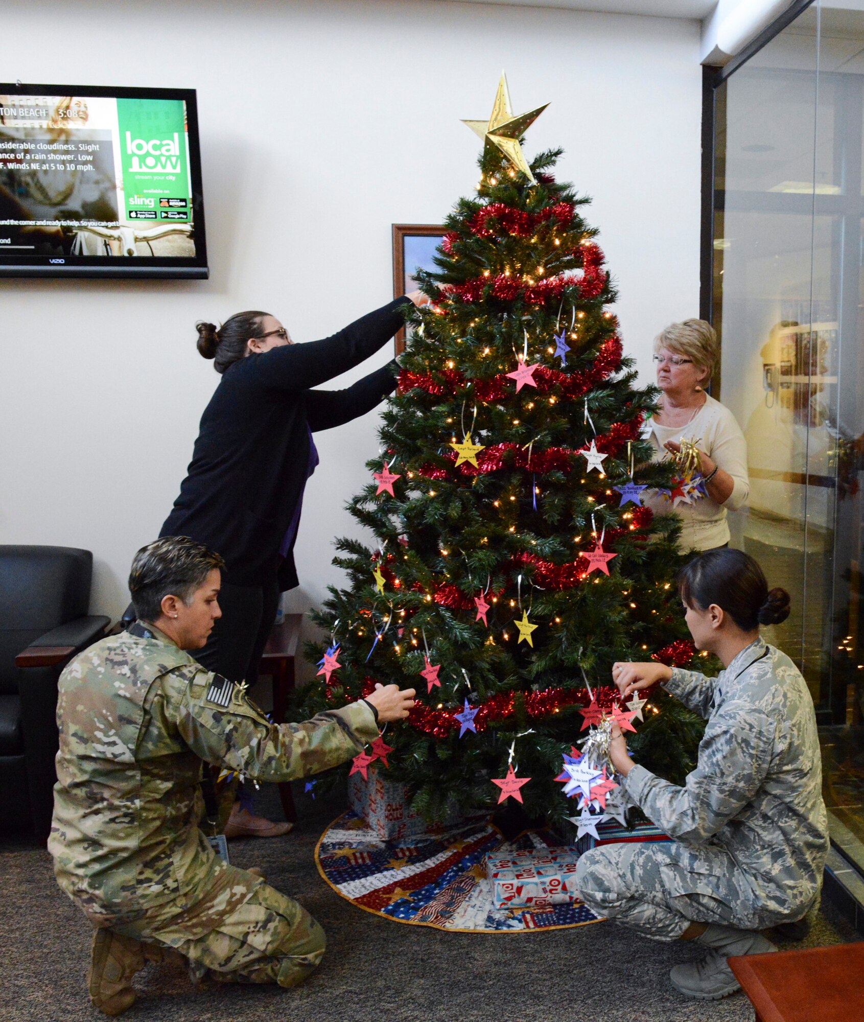 Air Force Special Operations Command members (four people) place stars on a Christmas tree