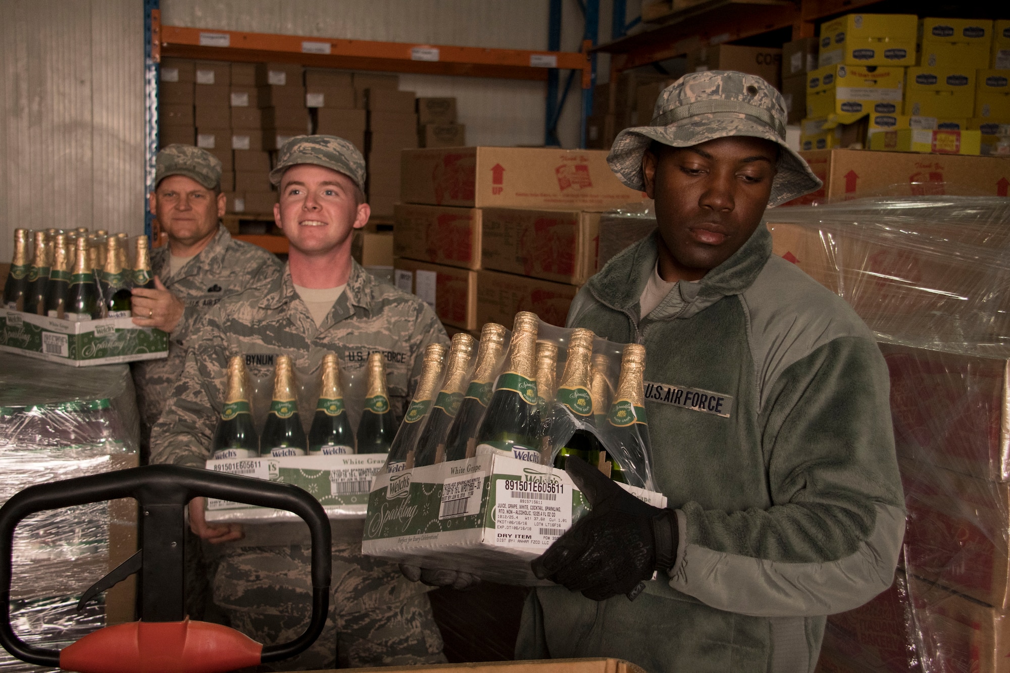 Airmen from the 386th Expeditionary Force Support Squadron carry sparkling grape juice through a storeroom Dec. 22, 2016 at an undisclosed location in Southwest Asia. These Airmen were assembling tri-walls of holiday meal items for forward-deployed service members (U.S. Air Force photo/Staff Sgt. Andrew Park)