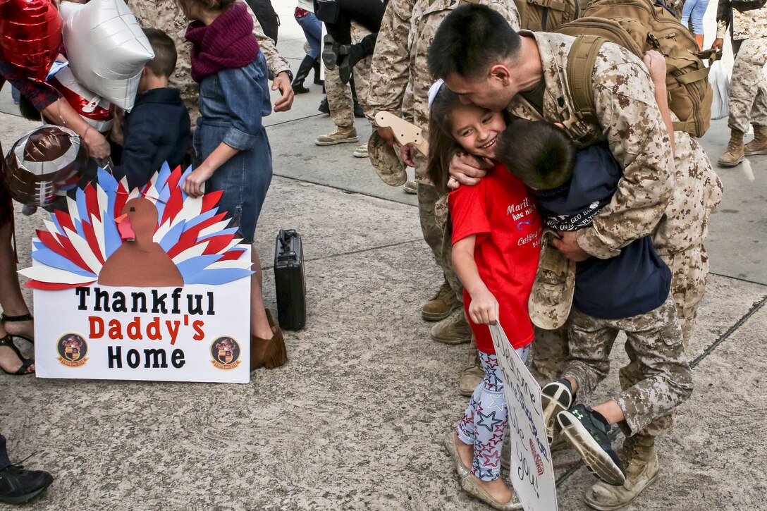 A Marine returns from deployment and hugs his family.
