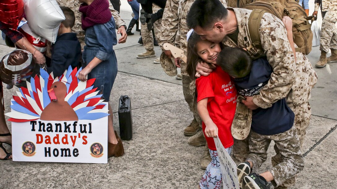 A Marine returns from deployment and hugs his family.