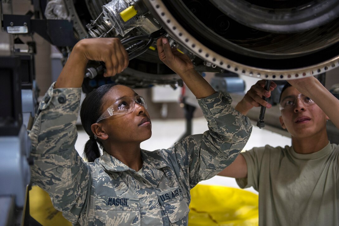An airman wires fuel nozzles on an aircraft engine.