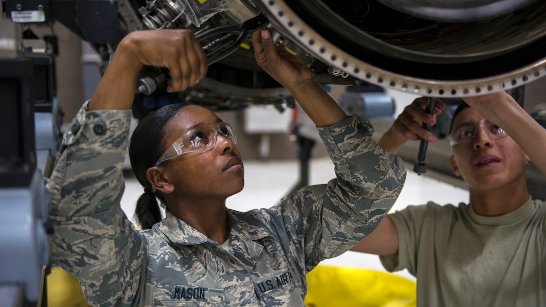 An airman wires fuel nozzles on an aircraft engine.