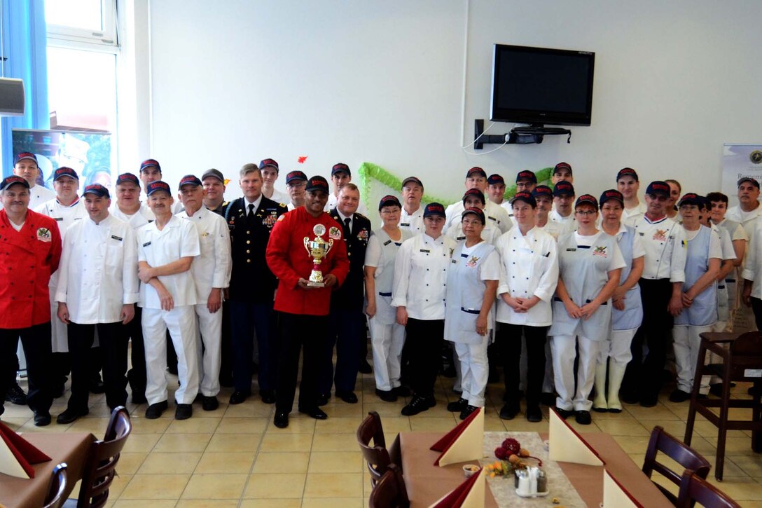 A large group photo of dining staff holding a trophy.