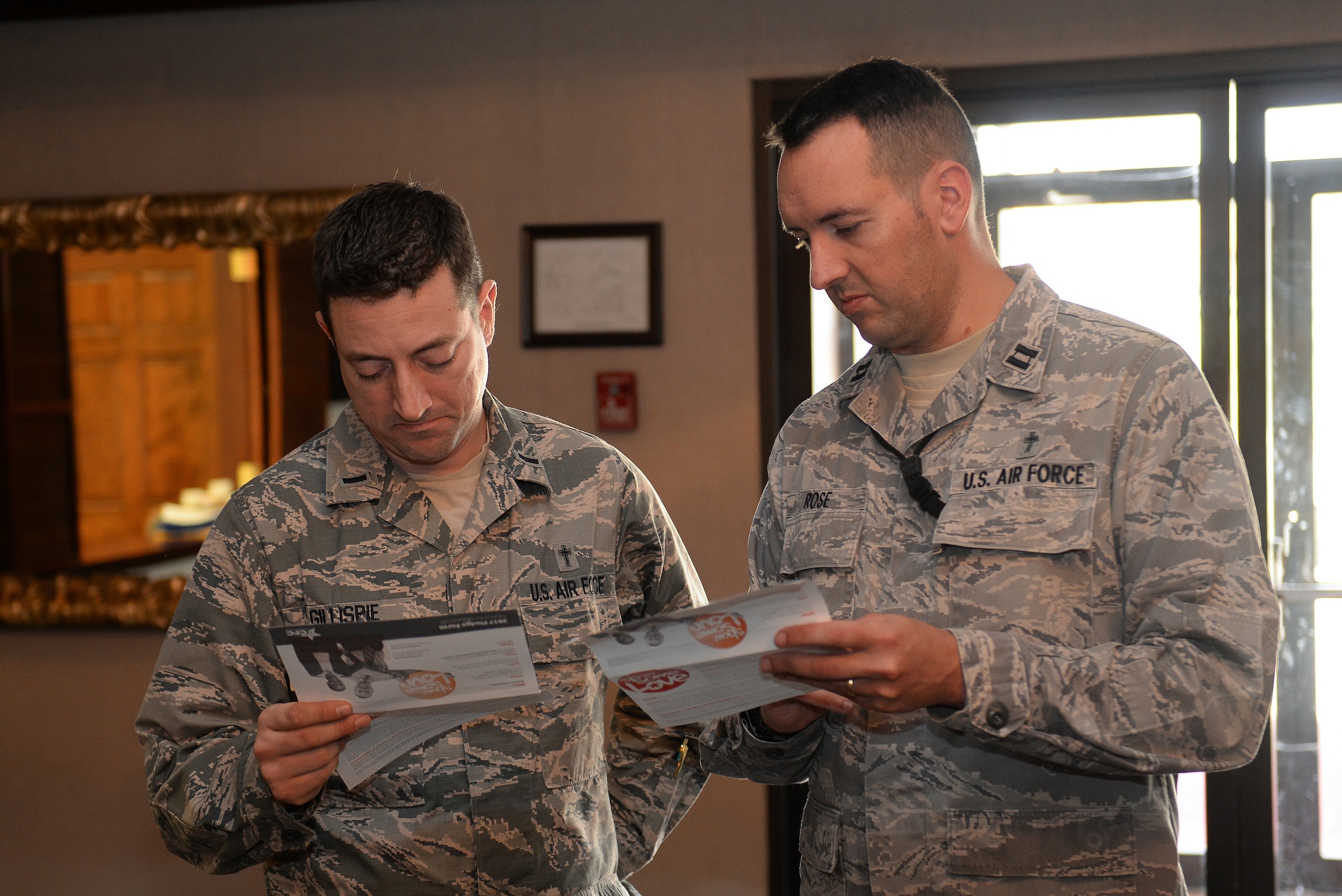 Chaplain (1st Lt.) John Gillispie, 55th Wing Chapel and Chaplain (Capt.) Robert Rose look through the list of charities for the 2017 Combined Federal Campaign at the CFC kick-off on Nov. 21, 2017 at the Patriot Club on Offutt AFB, Neb.