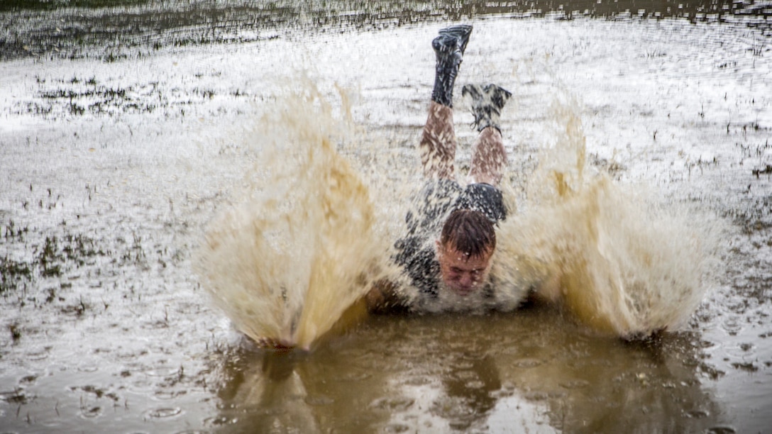 A Marine skids into a muddy pool of water