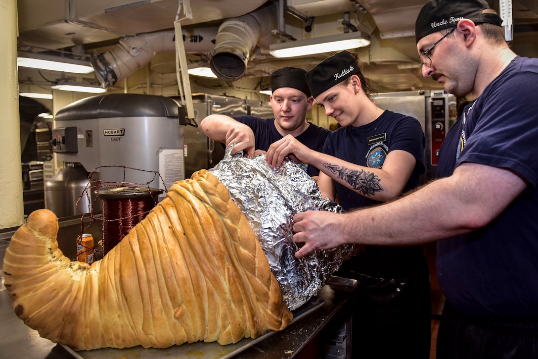Three sailors make a cornucopia for Thanksgiving dinner.