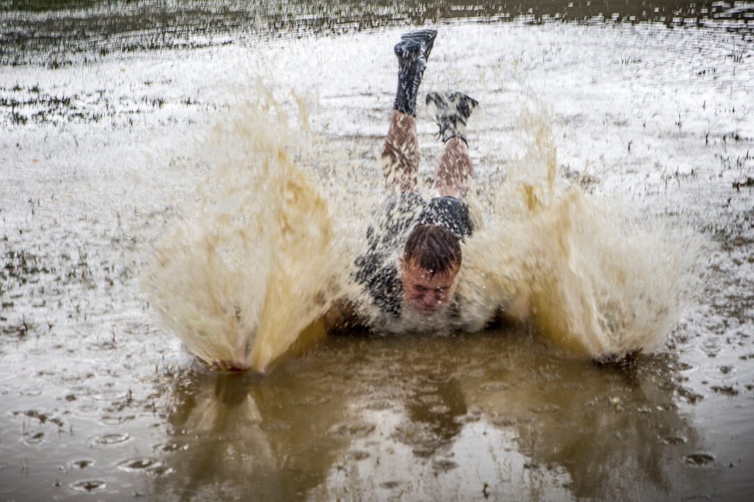 A Marine skids into a muddy pool of water