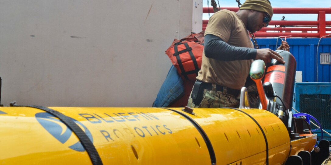 A technician performs maintenance on an unmanned underwater vehicle.
