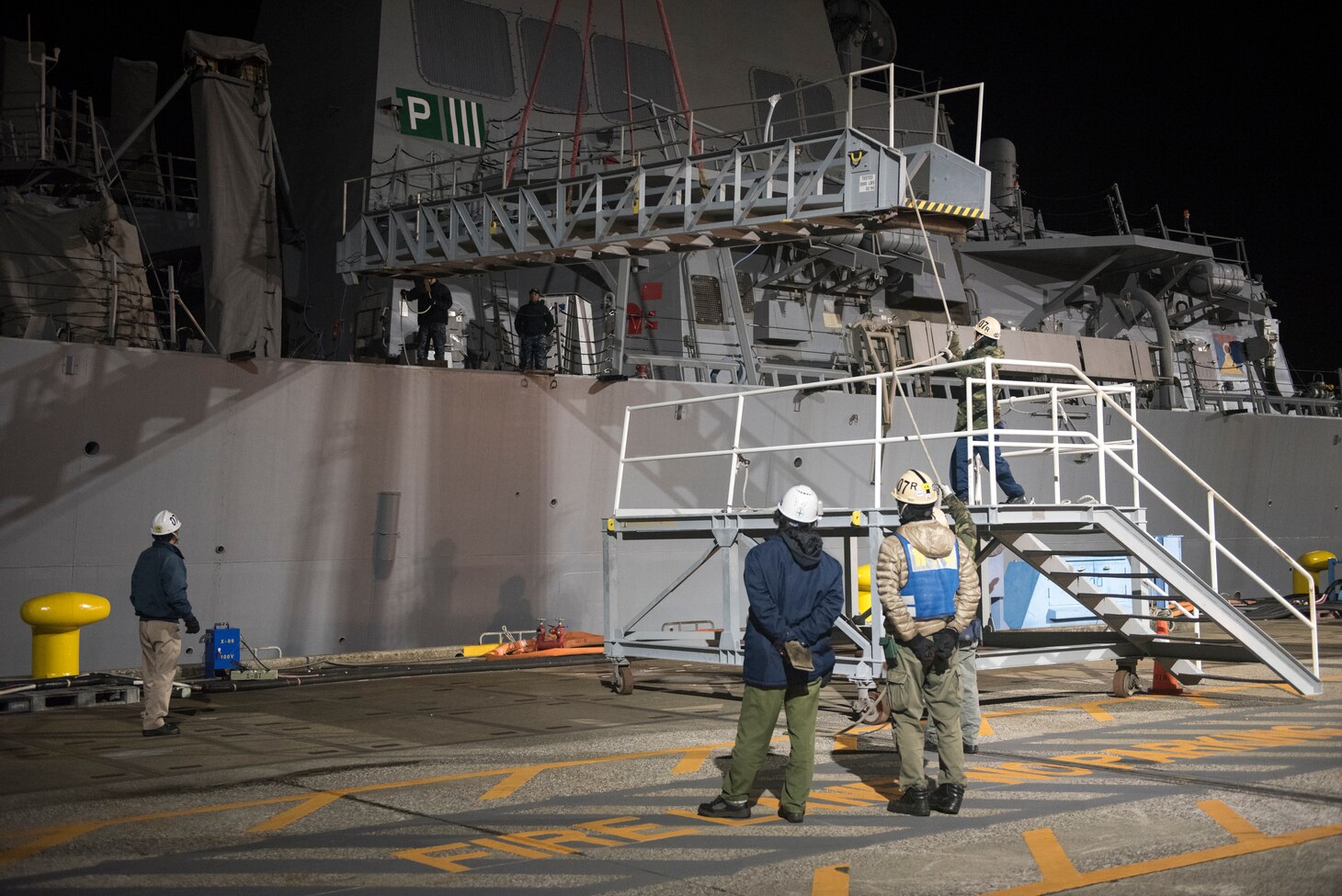 Workers remove the brow from the Arleigh Burke-class guided missile destroyer USS Fitzgerald (DDG 62) prior to being towed away from the pier at Fleet Activities (FLEACT) Yokosuka, Nov. 24, to meet heavy lift transport vessel Transshelf. Transshelf will transport Fitzgerald to Pascagoula, Mississippi for repairs.