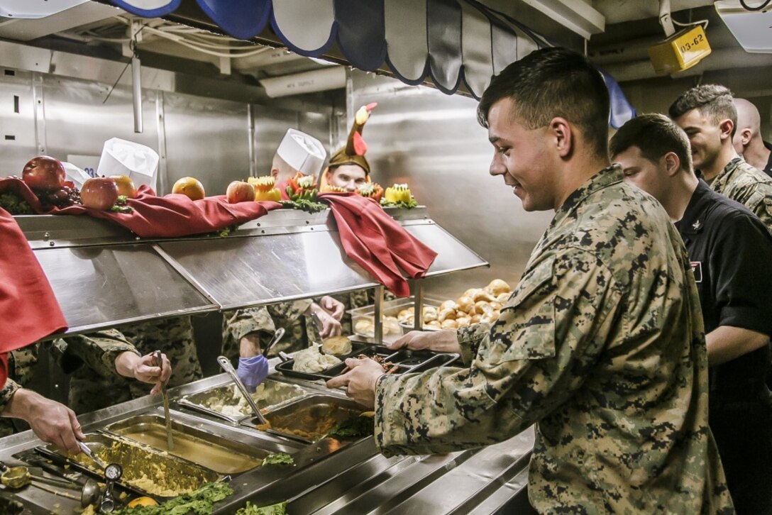 A service member puts food on his plate at a buffet.