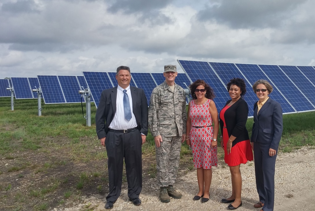 Stakeholders stand in front of solar panels